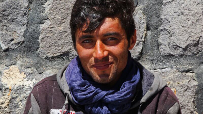An Afghan porter wearing a blue scarf smiles for the camera.