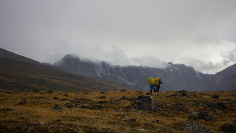 Far shot of two hikers ascending in to the wild mountains of Siberia.
