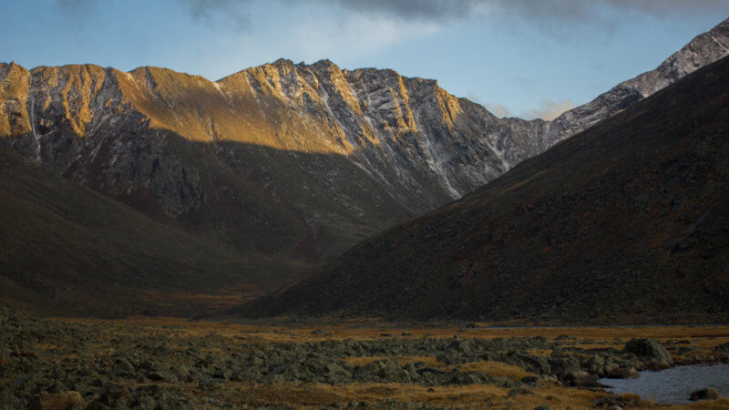 Late afternoon, overcast landscape photo of mountain plateau and rock peaks in background.