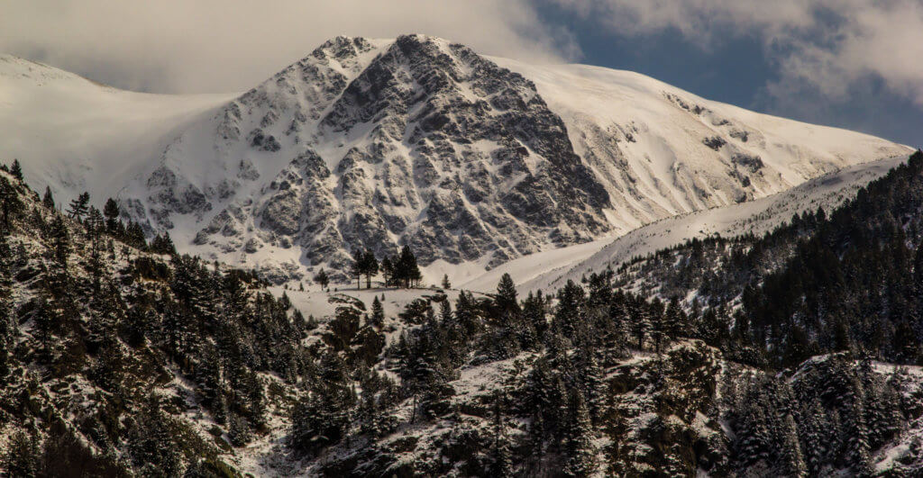 A large, imposing rock face near Kosovo, covered in snow.