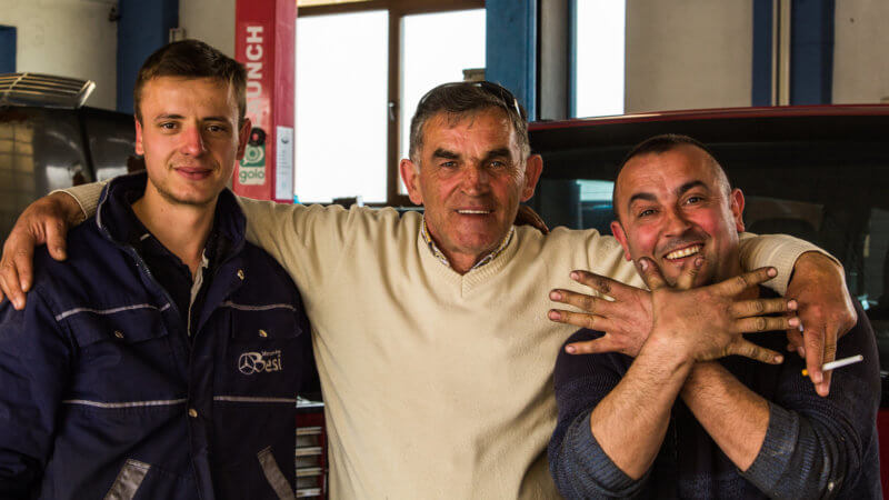 Three car mechanics in Kosovo posing for the camera.