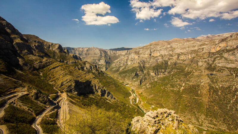 Giant limestone canyon in Albania with mountain road snaking through.