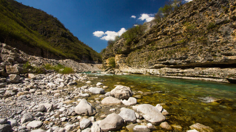 A clear blue alpine river flowing through Albanian valley.
