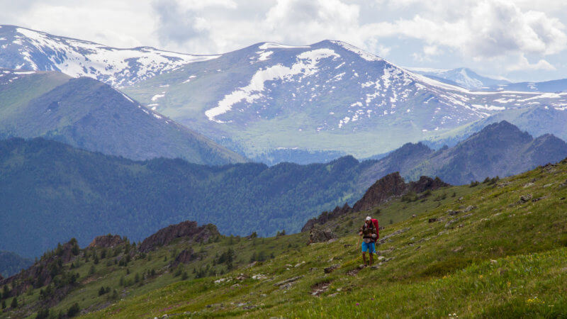 A hiker walking through alpine mountains in the summer.
