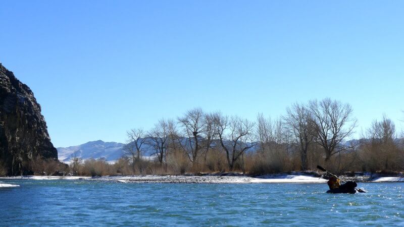 Winter time photo of packrafter paddling down the Khovd River.