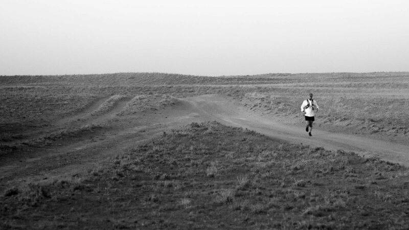 Jamie Maddison running past a rare junction point in the east-west dirt track that cuts across the Lower Saryesik Atyrau desert.