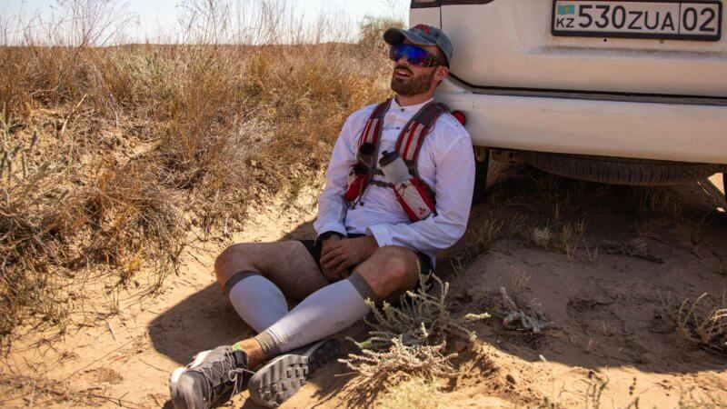 Jamie Maddison catching a short rest break and hiding from the blazing sun in the Saryesik Atyrau desert in Kazakhstan.