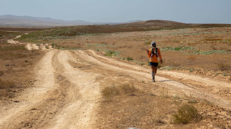 Tired after an ultra-run across a Kazakhstan desert, a runner gives the OK sign.
