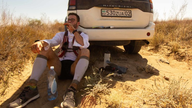 Desert runner Jamie pauses for a much needed rest break from running in the late summer's searing temperatures in Kazakhstan. Leaning against the car and exhausted.