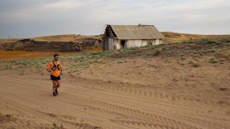 Jamie Maddison running past an old farm in the Saryesik-Atyrau Desert.