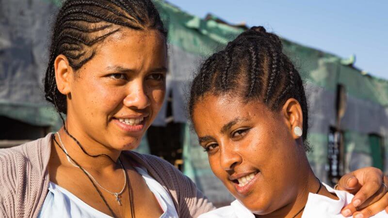 Portrait of two Ethiopian women with braided hair and white blouses.