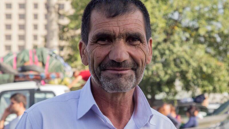 Tajik man with kind face and many wrinkles in a Dushanbe market.