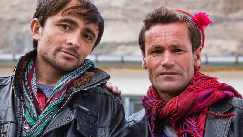 Two men wearing leather jackets and brightly coloured scarves.
